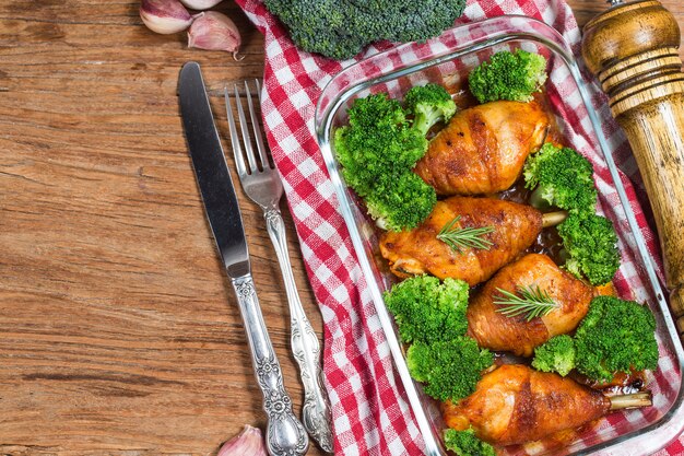 Piernas de pollo con las verduras en la tabla de madera.