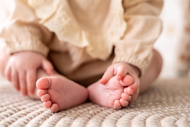 Foto las piernas sanas de los niños cierran los dedos de los pies de los niños y los talones de los niños en el fondo de la cama en tonos beige