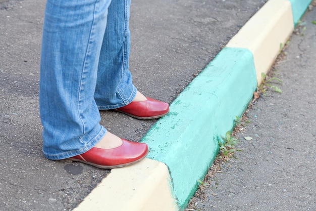 Piernas en zapatos rojos en la acera urbana en día de otoño