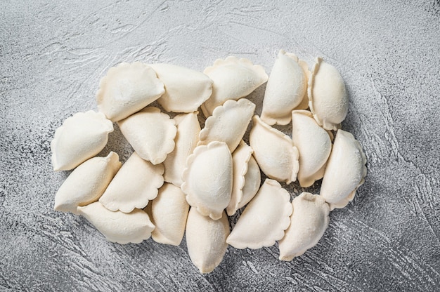 Pierogi de albóndigas congeladas crudas sobre una mesa de cocina. Fondo blanco. Vista superior. Copie el espacio.