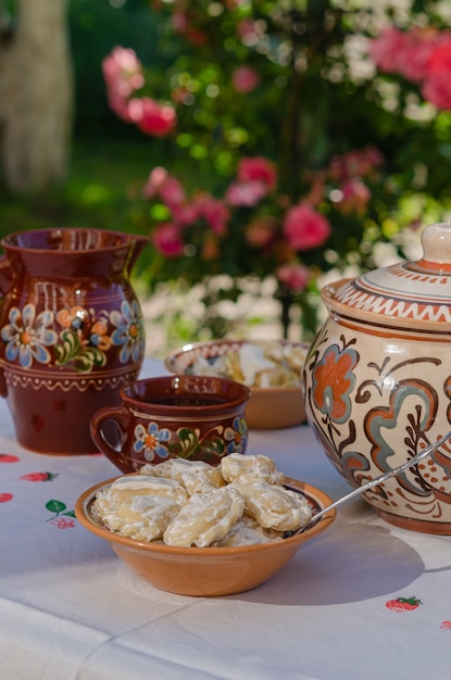 Pierogi casero en arcilla platos étnicos ucranianos sobre una mesa en el jardín de verano.