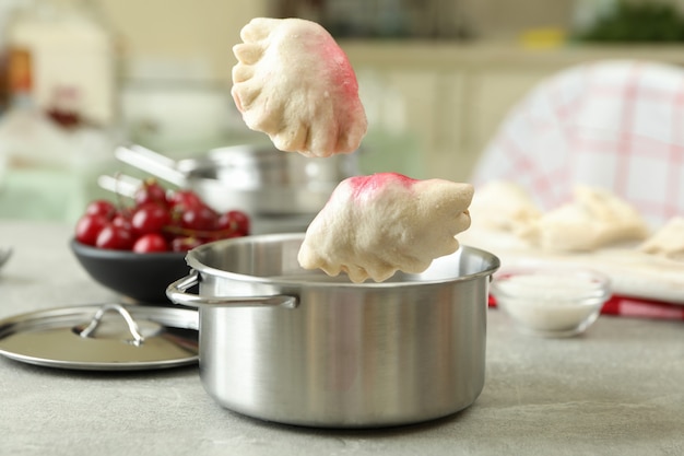 Pierogi con cerezas cayendo en una olla de metal