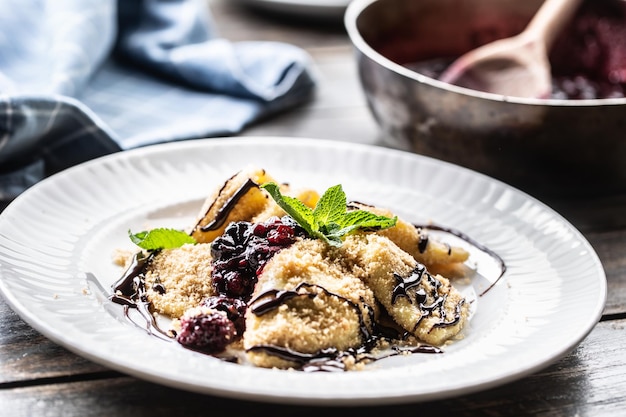 Pierogi recién hecho servido con salsa de frutos del bosque y hojas de menta encima.