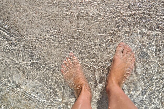 Pies en el agua en la arena