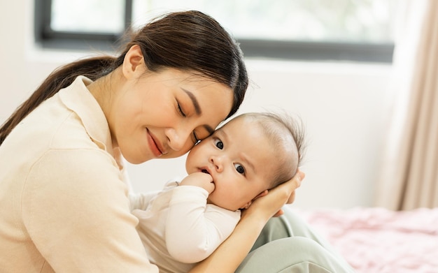 Los pies asiáticos de la madre y del bebé recién nacido están sonriendo y felices