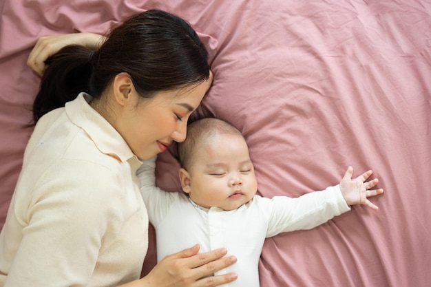 Los pies asiáticos de la madre y del bebé recién nacido están sonriendo y felices