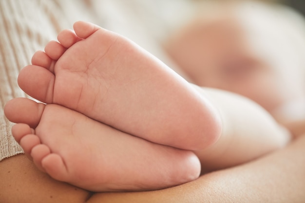 Pies de bebé caucásico, su madre lo abraza