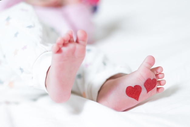 Pies de bebé con corazones en los pies Un bebé recién nacido está acostado en la cama