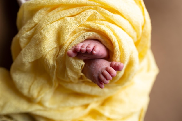 Los pies de un bebé están envueltos en una manta amarilla.