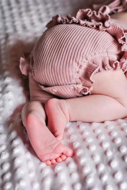 Los pies de un bebé están metidos en una manta. Pies de bebé desnudo de una niña en los pliegues.