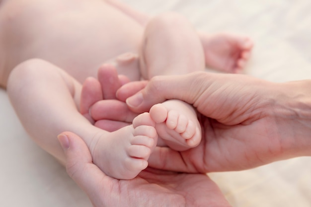 Pies de bebé en manos de la madre. Mamá y su hijo.