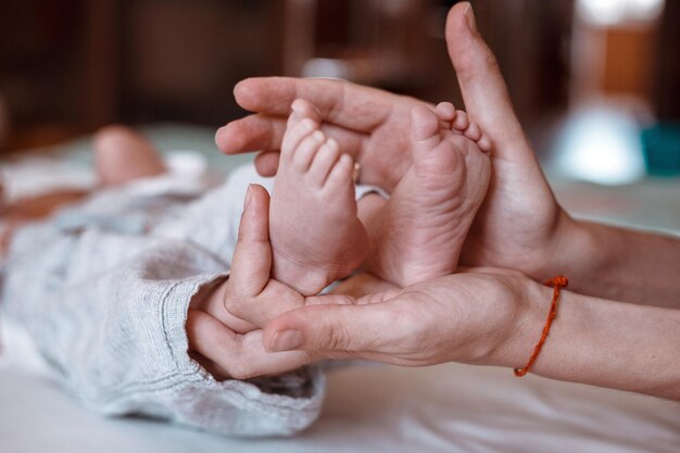 Pies de bebé en manos de la madre Pies de bebé recién nacido diminuto en primer plano de manos con forma femenina Mamá y su hijo Concepto de familia feliz Hermosa imagen conceptual de maternidad