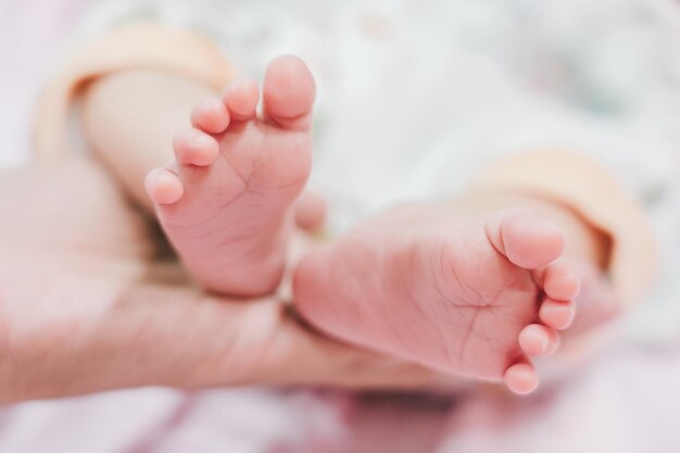 Foto pies de bebé en las manos de la madre pies pequeños de bebés recién nacidos en manos femeninas en forma de mano de cerca mamá y su hijo concepto de familia feliz