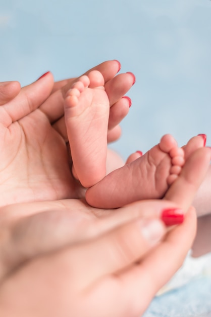 Pies del bebé en manos de la madre