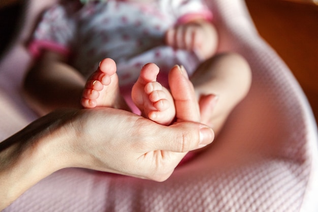 Pies de bebé en manos de la madre