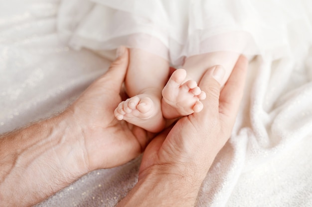 Pies de bebé en manos del padre. Pies del pequeño bebé recién nacido en primer plano de manos masculinas. Papá y su hijo. Concepto de familia feliz. Hermosa imagen conceptual de la paternidad