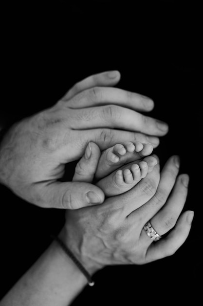Pies de bebé en manos de los padres. Idea de fotografía de recién nacido. Idea de foto familiar. foto en blanco y negro