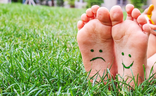 Los pies del bebé con patrón de pintura están sonrientes y tristes sobre la hierba verde. Enfoque selectivo. naturaleza.