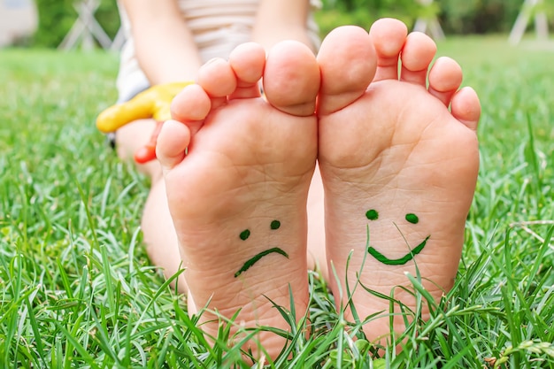 Los pies del bebé con patrón de pintura están sonrientes y tristes sobre la hierba verde. Enfoque selectivo. naturaleza.