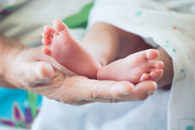 Pies de bebé recién nacido en la mano de la abuela con ternura