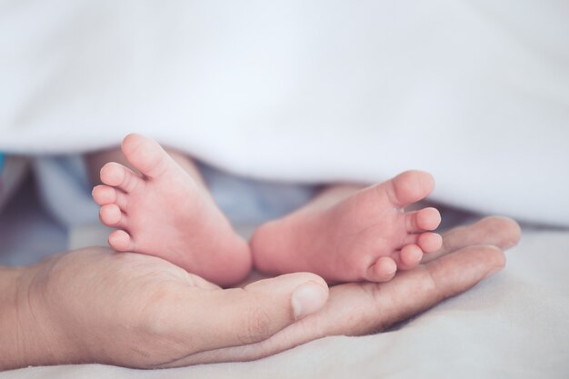 Pies de bebé recién nacido en la mano de la madre con ternura