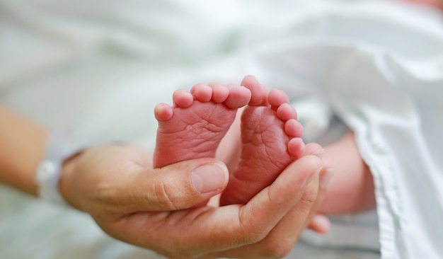 Pies de bebé recién nacido en la mano de la madre.