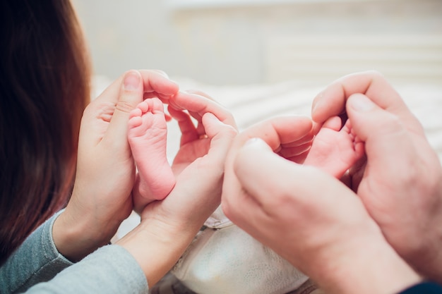 Pies de bebé recién nacido en la mano de los padres