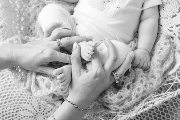 Pies de bebé recién nacido en manos de la madre Madre sosteniendo las piernas del niño en las manos Concepto de familia feliz