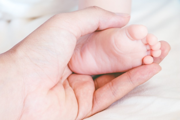 Pies de bebé recién nacido en las manos de la madre