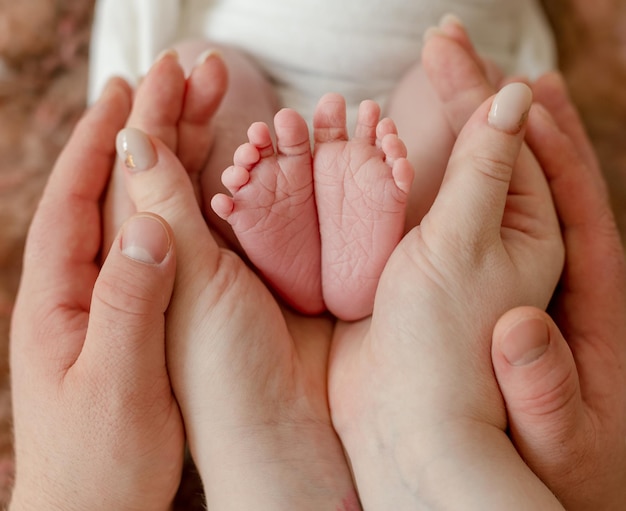 Pies de bebé recién nacido en manos de los padres