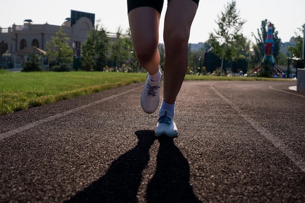 Pies de corredor corriendo en el primer plano de la carretera en los zapatos mujer fitness sunrise jogging entrenamiento welness