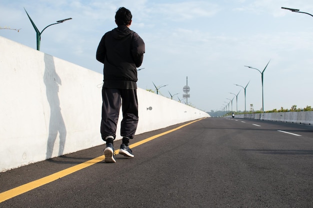 Pies de corredor de hombre corriendo en la carretera para trotar al aire libre