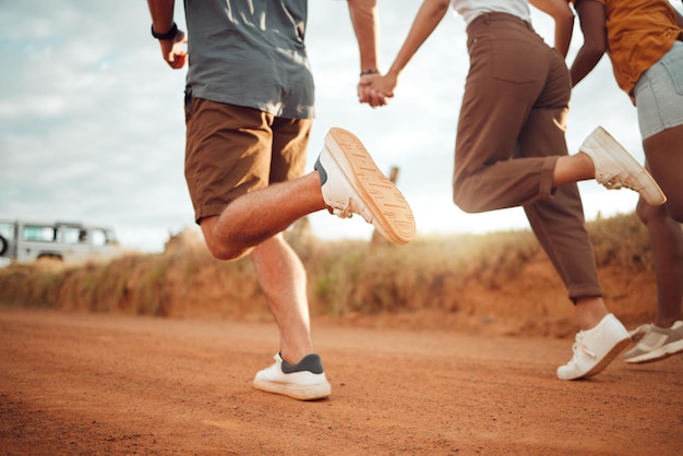 Pies corriendo y amigos tomados de la mano de vacaciones en el campo de Italia juntos Piernas de un grupo de personas jugando en una carrera con apoyo libertad y aventura en un viaje por carretera en la naturaleza