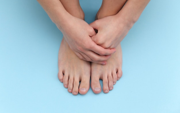 Pies descalzos femeninos sobre fondo azul. Concepto de cuidado de la belleza