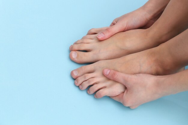 Foto pies descalzos femeninos sobre fondo azul. concepto de cuidado de la belleza