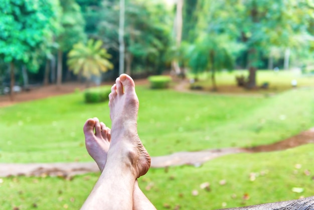 Pies descalzos de hombre descansando sobre fondo de césped verde Parque Nacional Erawan Tailandia Relax concepto de estilo de vida