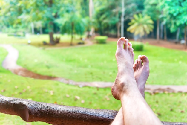 Pies descalzos de hombre descansando sobre fondo de césped verde Parque Nacional Erawan Tailandia Relax concepto de estilo de vida