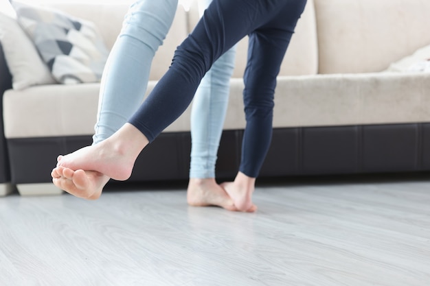 Pies descalzos, mamá e hija bailando en el piso de la casa closeup