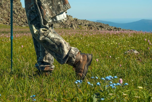 Pies de excursionista en botas de trekking viajando a través de la pradera alpina en las montañas, cerrar