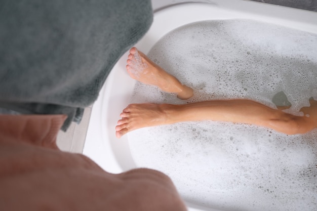 Foto pies femeninos en el agua en la vista superior del primer del baño