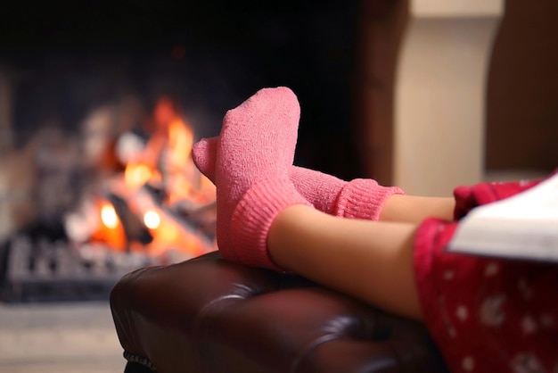 Pies femeninos en calcetines cerca de la chimenea