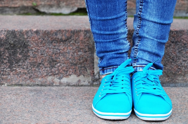 Pies femeninos en gumshoes en escaleras de piedra