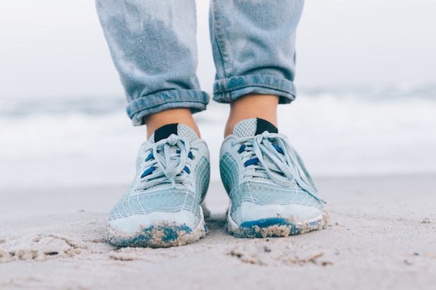 Pies femeninos en jeans mojados y zapatillas de deporte