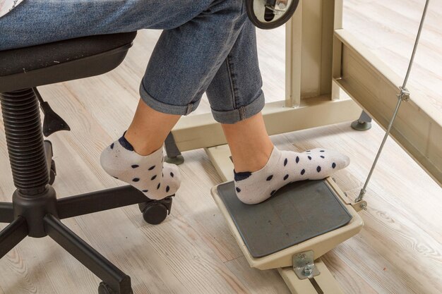 Pies femeninos en el pedal de un motor de máquina de coser