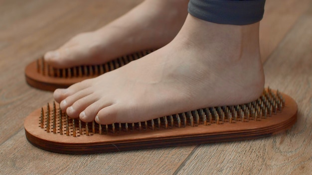 Pies femeninos de pie en tablas con uñas cerca de los medios de comunicación mujer descalza de pie en uñas de yoga