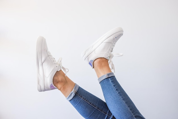 Pies femeninos en zapatillas levantadas aislado sobre fondo blanco.