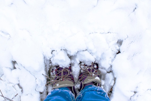 Pies femeninos en zapatos de invierno de pie en un ventisquero de nieve fresca Paseo de invierno