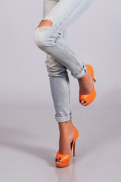 Foto pies femeninos en zapatos naranjas y jeans, look de moda