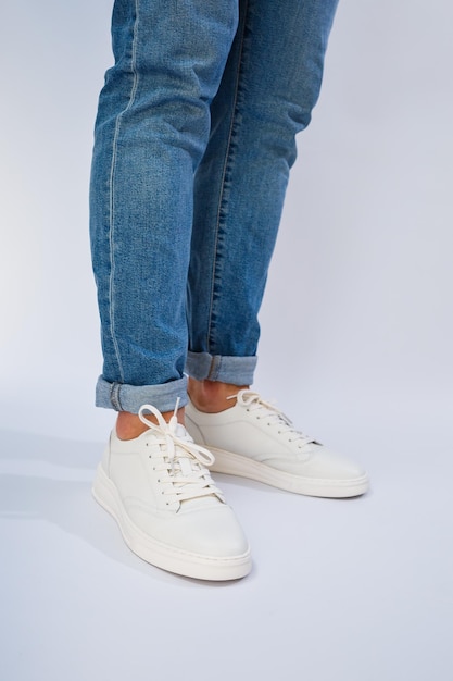 Pies de hombre en zapatillas deportivas blancas para el día a día fabricadas en piel natural con cordones.