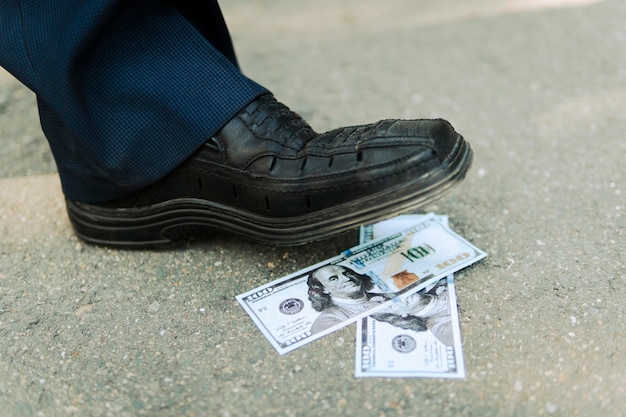 Pies de hombre en zapatos negros pasando por pista de dinero primer plano un hombre encuentra dinero en la carretera Un hombre de negocios rico va por dinero concepto de dinero bajo los pies